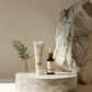 Skincare products on a marble surface with a stone and plant in the background